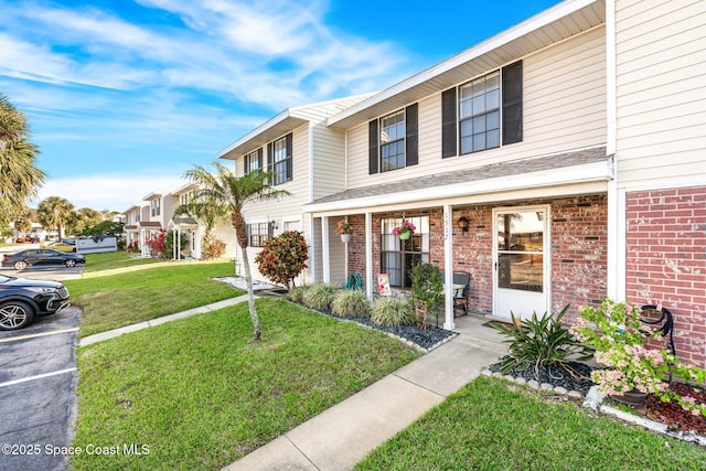 townhome / multi-family property featuring uncovered parking, brick siding, and a front lawn