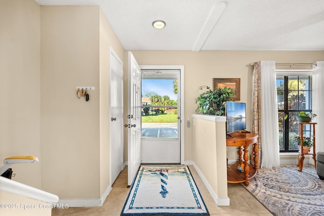 doorway featuring light tile patterned flooring, a textured ceiling, and baseboards