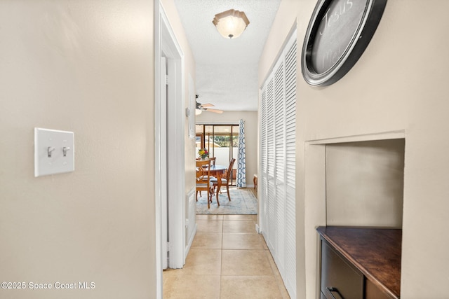 hallway with light tile patterned floors and a textured ceiling