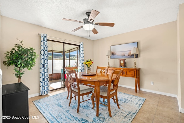 dining area with a textured ceiling, ceiling fan, light tile patterned floors, and baseboards