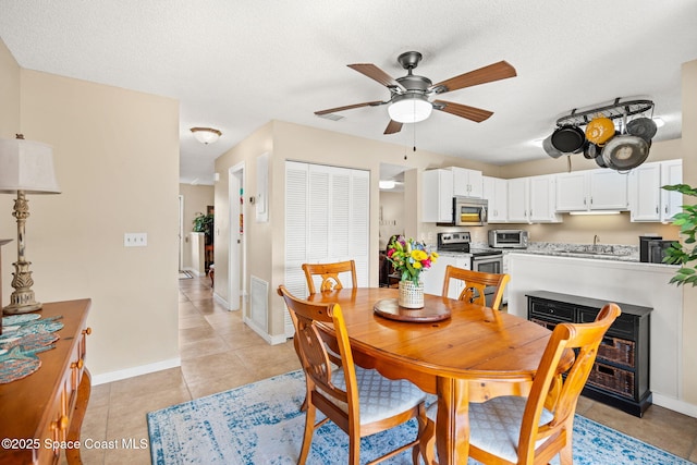 dining space featuring a textured ceiling, ceiling fan, light tile patterned flooring, visible vents, and baseboards