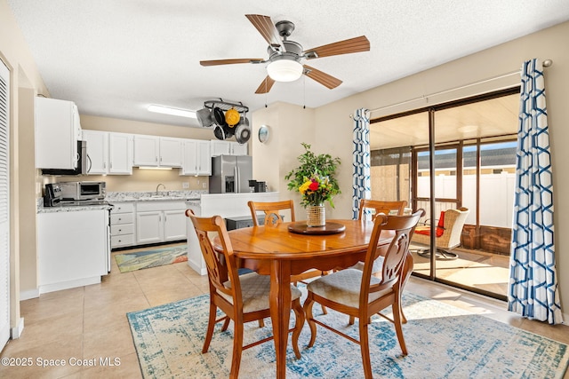 dining area with light tile patterned floors, ceiling fan, and a textured ceiling