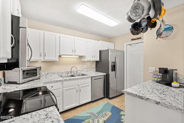 kitchen featuring a toaster, appliances with stainless steel finishes, white cabinets, a sink, and a textured ceiling