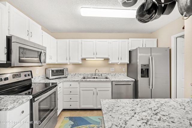 kitchen with a textured ceiling, a toaster, a sink, white cabinetry, and appliances with stainless steel finishes