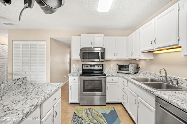 kitchen with a toaster, visible vents, appliances with stainless steel finishes, white cabinetry, and a sink