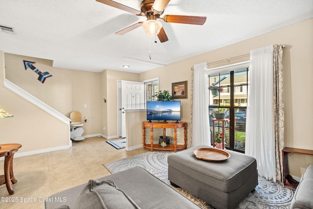 living area with baseboards, visible vents, stairway, a textured ceiling, and light tile patterned flooring