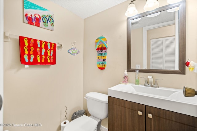 half bathroom featuring a textured ceiling, visible vents, vanity, and toilet