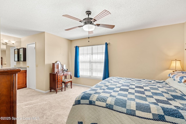 bedroom with light colored carpet, connected bathroom, a textured ceiling, and baseboards