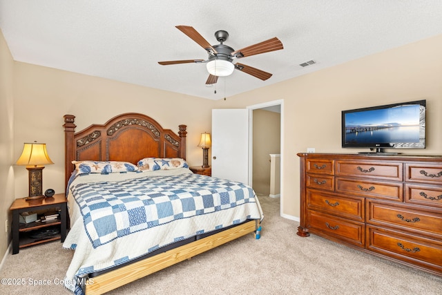 bedroom with a textured ceiling, light colored carpet, a ceiling fan, baseboards, and visible vents