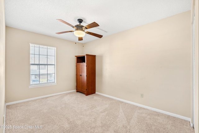 spare room featuring light carpet, a textured ceiling, a ceiling fan, and baseboards