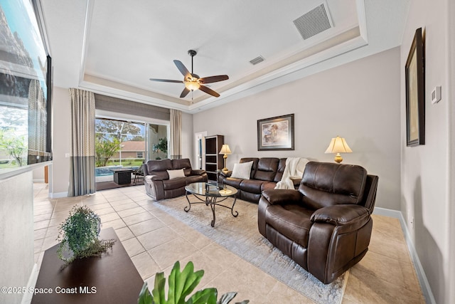 living area featuring light tile patterned floors, visible vents, a tray ceiling, and baseboards