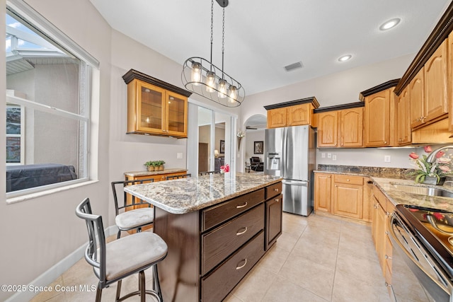 kitchen with arched walkways, range with electric cooktop, a sink, a kitchen island, and stainless steel refrigerator with ice dispenser