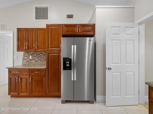 kitchen featuring light tile patterned flooring, stainless steel refrigerator with ice dispenser, visible vents, and light stone countertops