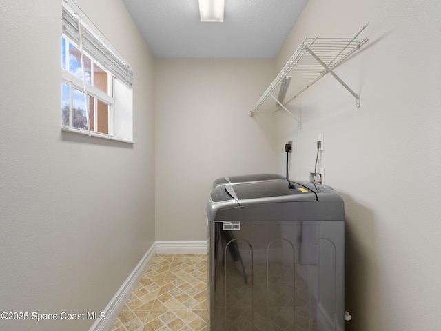 clothes washing area with laundry area, baseboards, and washer and clothes dryer