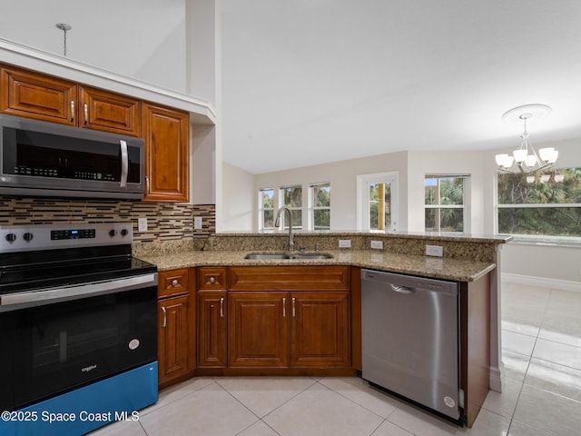 kitchen with stainless steel appliances, light stone counters, backsplash, and a sink