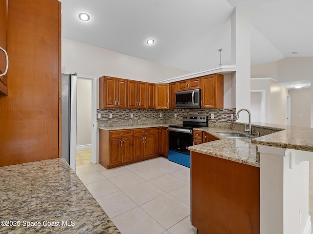 kitchen featuring lofted ceiling, light stone counters, a peninsula, stainless steel appliances, and a sink