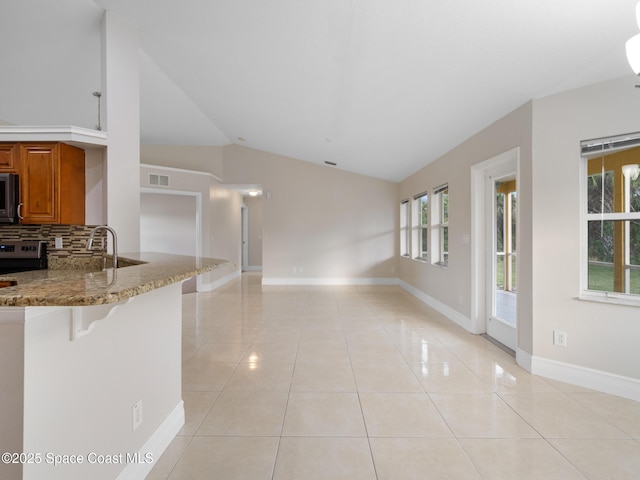 kitchen featuring visible vents, backsplash, brown cabinetry, light tile patterned flooring, and light stone countertops