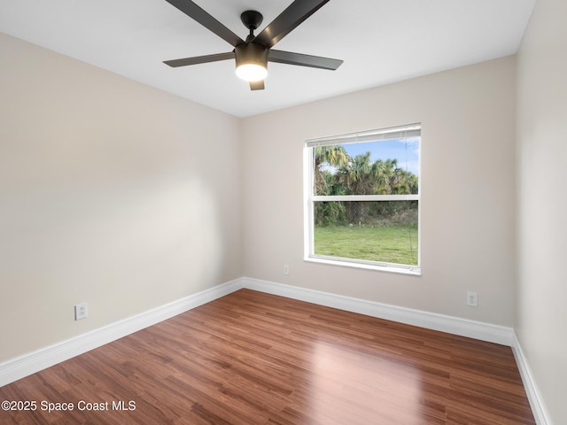 empty room with ceiling fan, wood finished floors, and baseboards