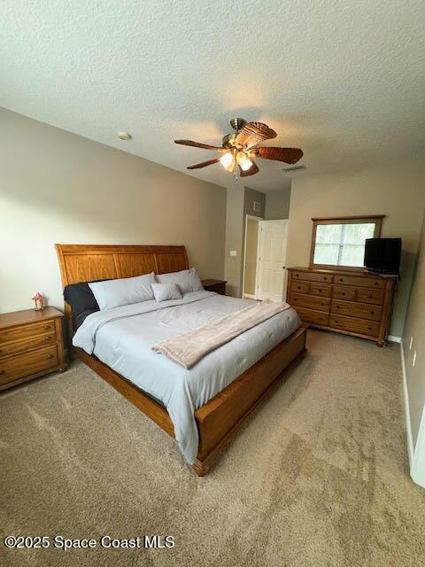 carpeted bedroom featuring ceiling fan, baseboards, and a textured ceiling