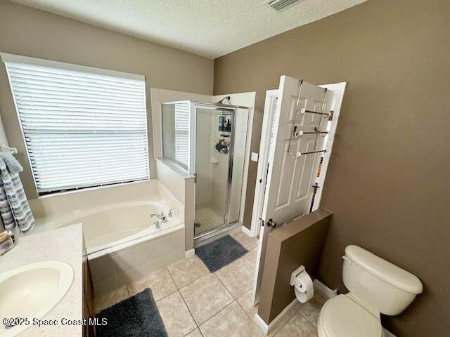 bathroom featuring tile patterned floors, toilet, a stall shower, a textured ceiling, and a bath