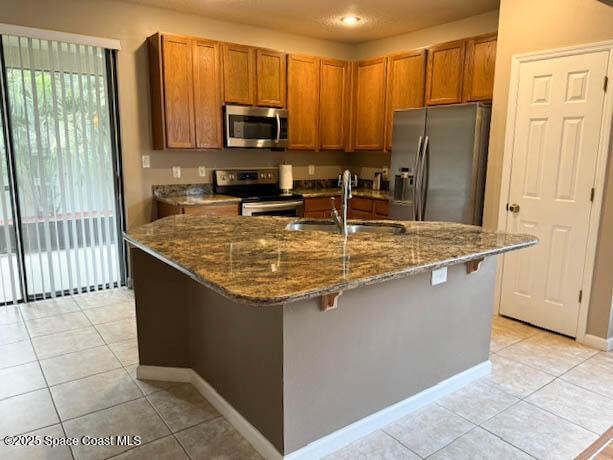 kitchen featuring a sink, stainless steel appliances, brown cabinets, and light tile patterned floors