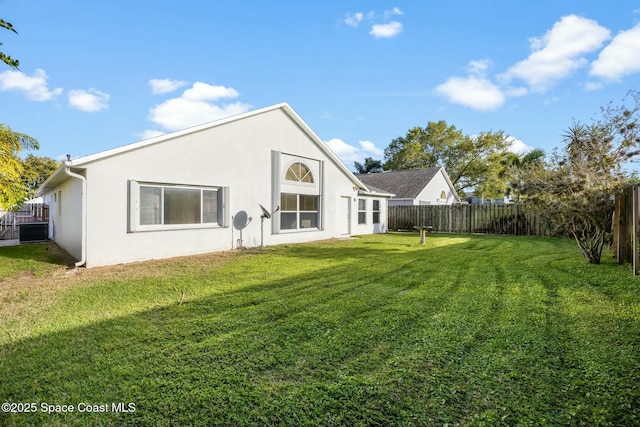 rear view of property with stucco siding, a fenced backyard, and a yard