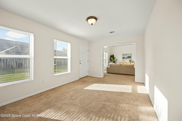 entryway featuring baseboards, visible vents, and light colored carpet