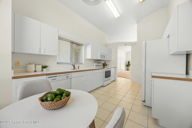 kitchen featuring white appliances, light tile patterned floors, white cabinets, light countertops, and a sink