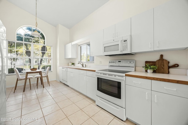 kitchen featuring white appliances, light tile patterned floors, white cabinets, lofted ceiling, and light countertops