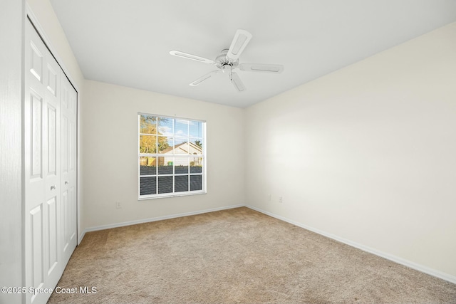 unfurnished bedroom with ceiling fan, a closet, carpet, and baseboards