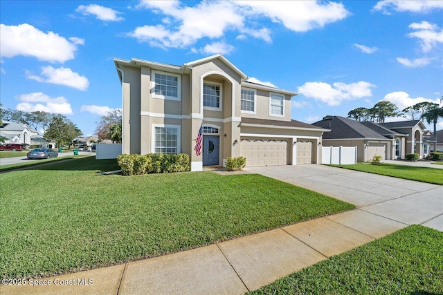 traditional-style home with a garage, a front yard, concrete driveway, and stucco siding