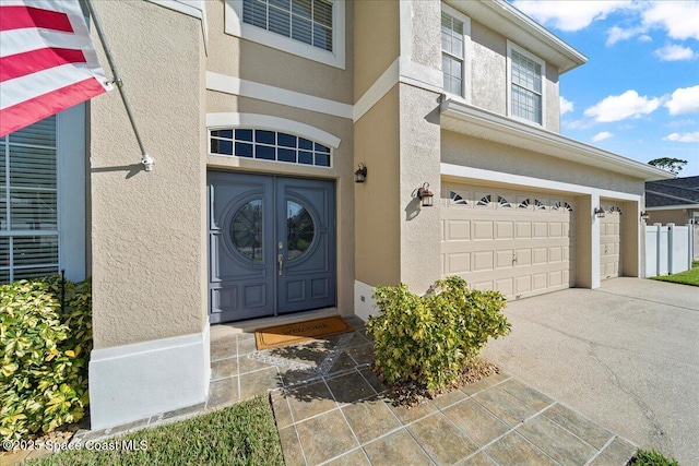 entrance to property featuring driveway, an attached garage, and stucco siding