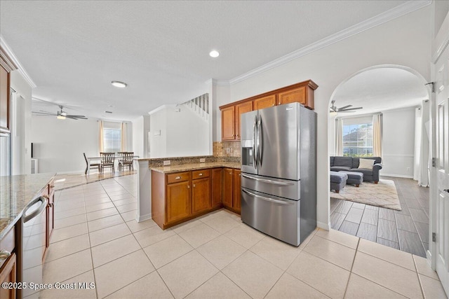 kitchen featuring a peninsula, brown cabinetry, stainless steel appliances, and open floor plan