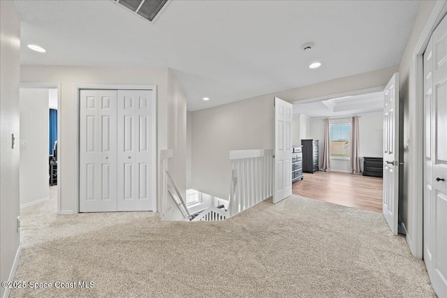 hall with light carpet, recessed lighting, visible vents, and an upstairs landing