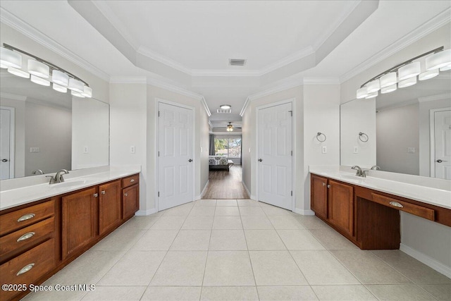 ensuite bathroom with a raised ceiling, ensuite bathroom, ornamental molding, a sink, and tile patterned flooring