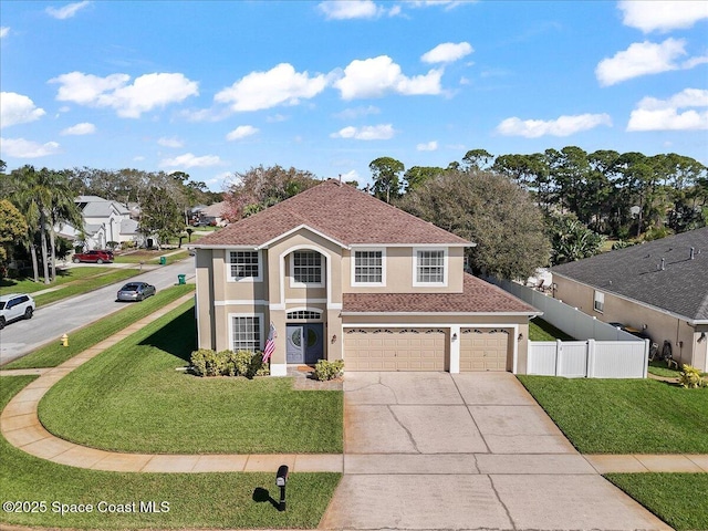 view of front of home featuring a front yard, concrete driveway, fence, and stucco siding