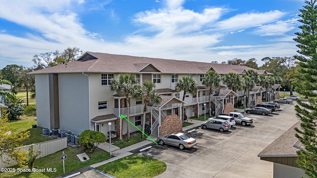 view of building exterior featuring uncovered parking and central AC unit