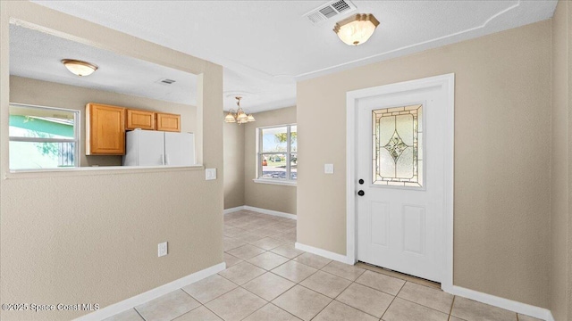 foyer with baseboards, visible vents, a chandelier, and light tile patterned flooring