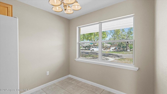 unfurnished room with light tile patterned floors, baseboards, and an inviting chandelier