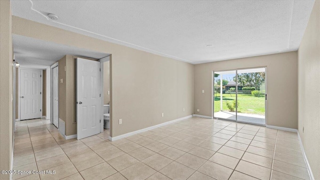 spare room with baseboards, a textured ceiling, and light tile patterned flooring