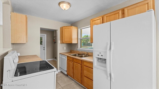 kitchen with white appliances, light tile patterned floors, light countertops, a textured ceiling, and a sink