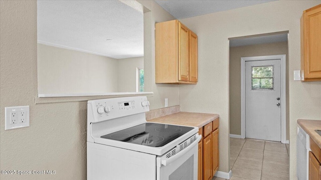 kitchen featuring a healthy amount of sunlight, light tile patterned floors, light countertops, and white range with electric cooktop