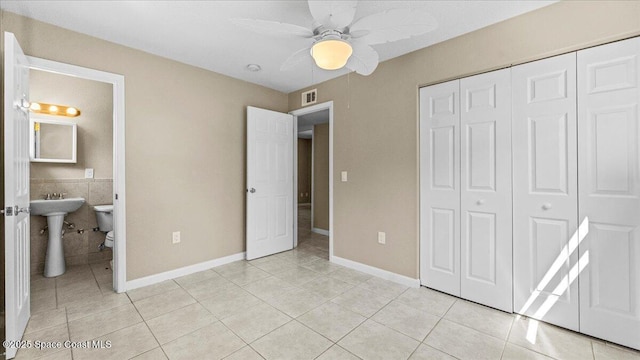 unfurnished bedroom with visible vents, connected bathroom, ceiling fan, a closet, and light tile patterned flooring