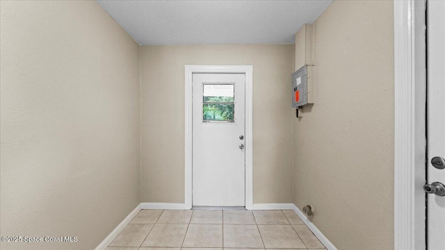 doorway to outside with a textured ceiling, baseboards, and light tile patterned floors