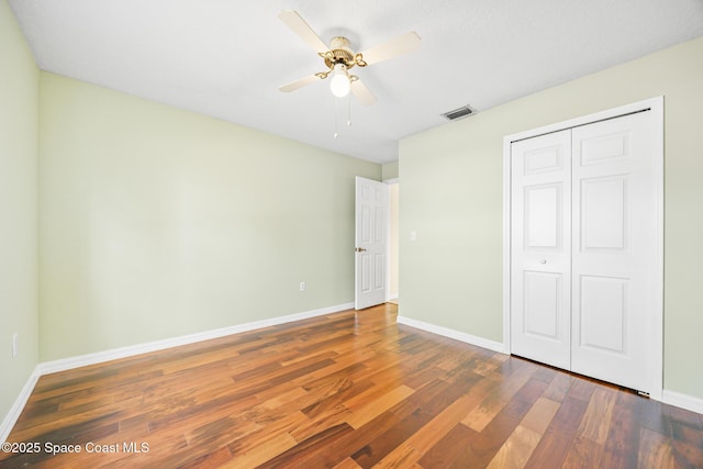 unfurnished bedroom with baseboards, a closet, visible vents, and wood finished floors