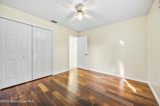 unfurnished bedroom with baseboards, a closet, visible vents, and hardwood / wood-style floors