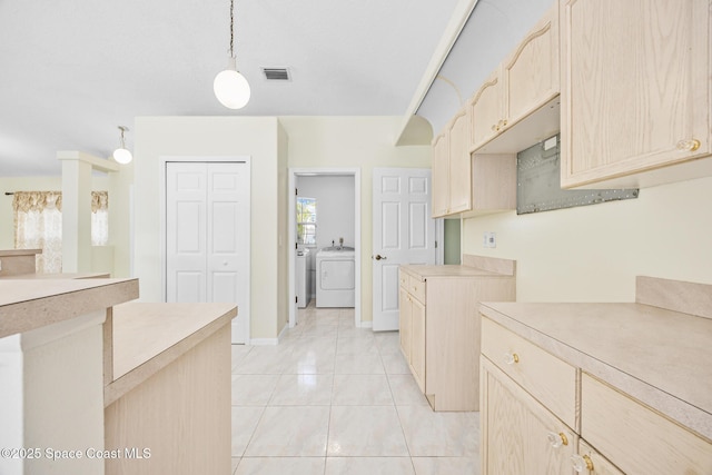 kitchen with light countertops, separate washer and dryer, light brown cabinets, and visible vents