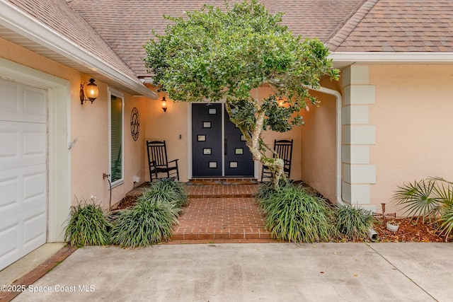 property entrance with a shingled roof and stucco siding