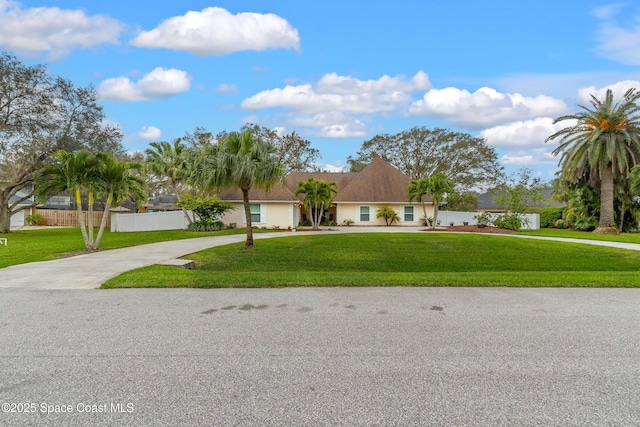 view of front of property with concrete driveway, fence, and a front lawn