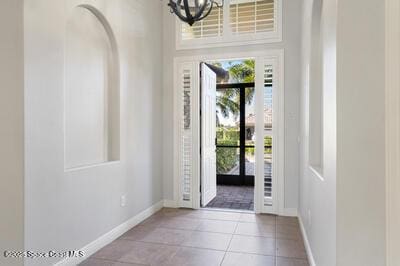 foyer featuring an inviting chandelier, light tile patterned flooring, and baseboards